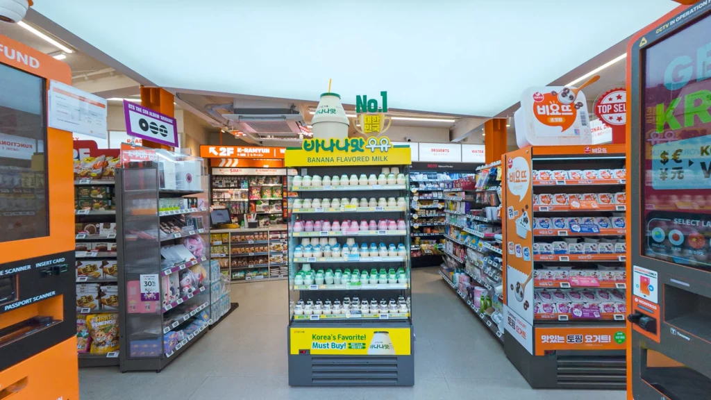 First-floor interior of Emart24 K-Food Lab Myeongdong with Banana Flavored Milk center display, Viyott stand, and WOWPASS kiosk.