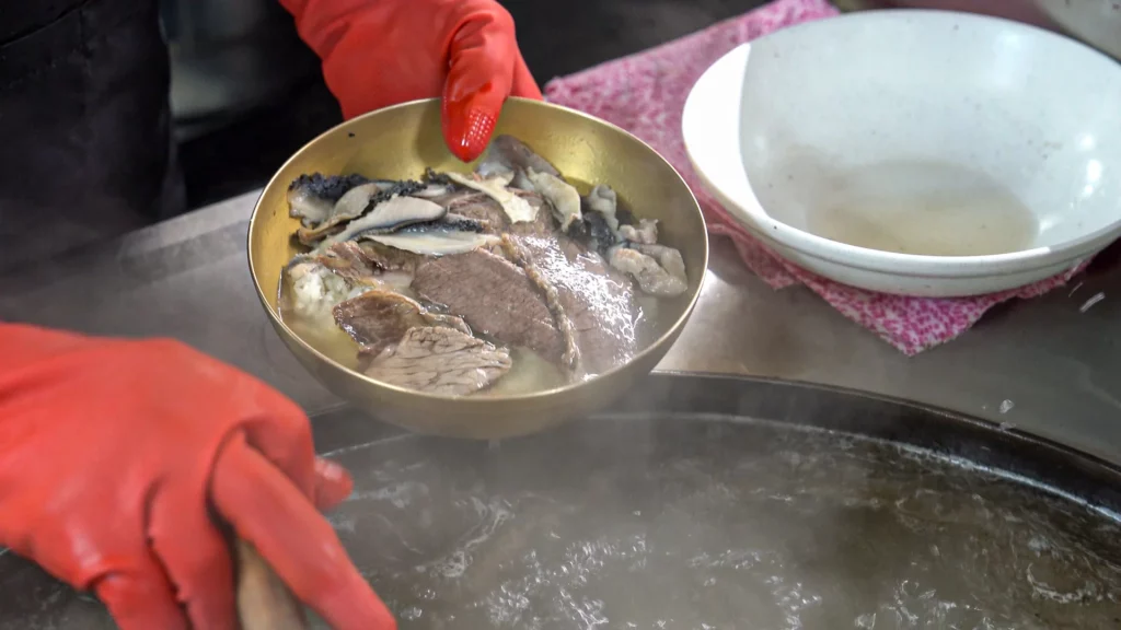 : Toryeom in action — a brass bowl of rice and Hanwoo brisket warmed in simmering broth at Hadongkwan Myeongdong.
