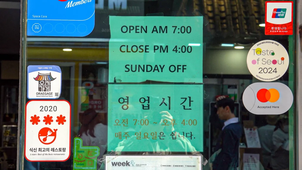 Hadongkwan's storefront notice — Open AM 7:00, Close PM 4:00, Sunday off — alongside Michelin and Taste of Seoul 2024 stickers.