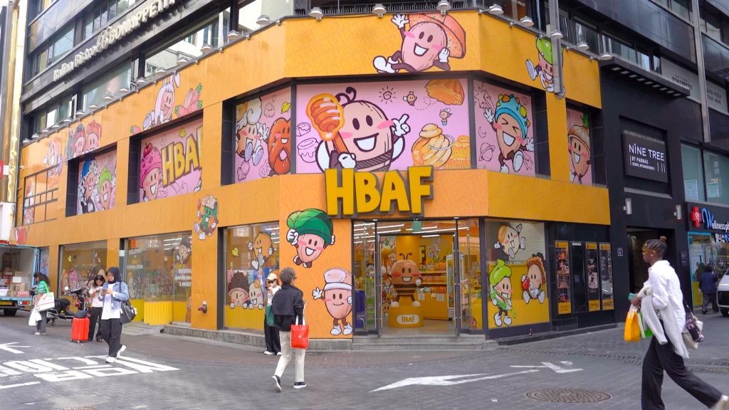 Wide view of the HBAF Almond Store Myeongdong No.3 corner building with giant bee-almond mascot statue by the entrance.
