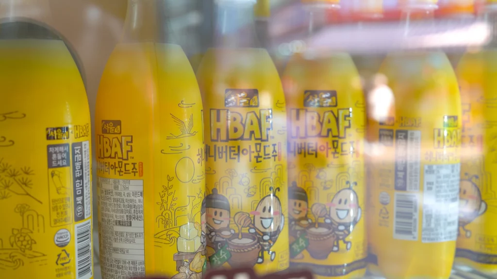 Detailed label view of HBAF Honey Butter Almond Makgeolli bottles showing 5% ABV and Seoul Jangsoo collaboration artwork.