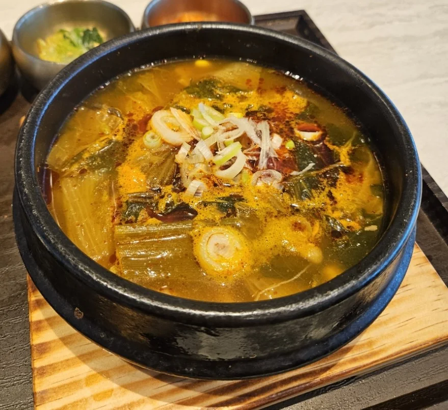 A steaming hot bowl of Eolkeun Sogogi Haejangguk topped with fresh green onions, served at an Incheon Airport Korean restaurant.