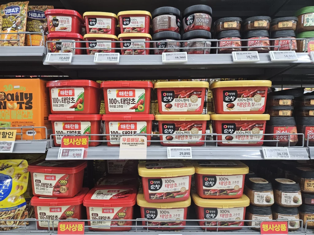 Multiple shelves of Korean gochujang (fermented chili paste) containers in various brands and sizes, the fermented ingredient that gives Korean ramyun its deep, complex spicy flavour.