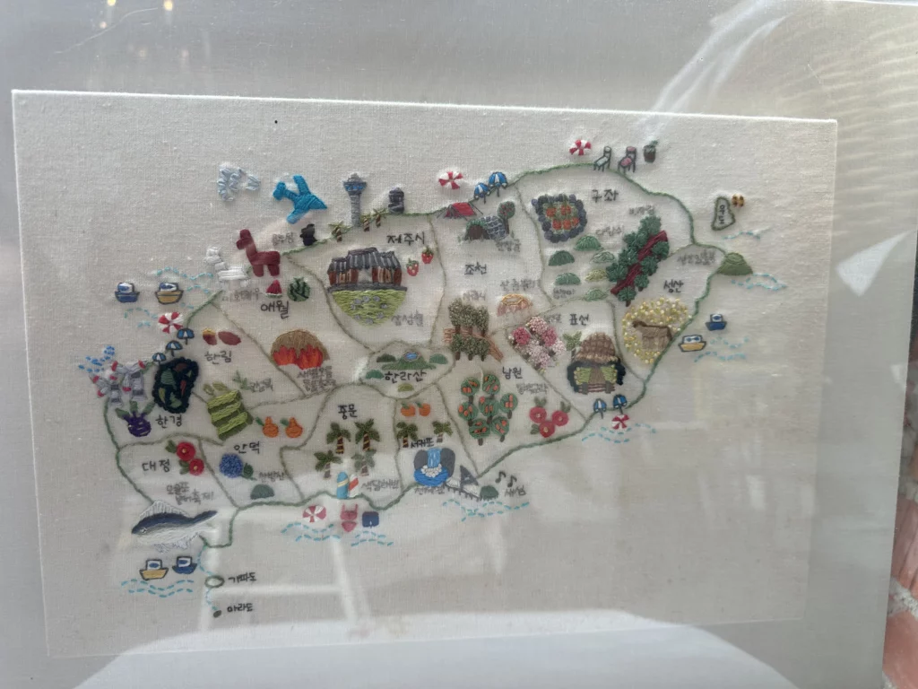 Embroidered Jeju Island map at jeju brunch cafe Tangerine showing regions, tangerine groves, and Hallasan landmarks.