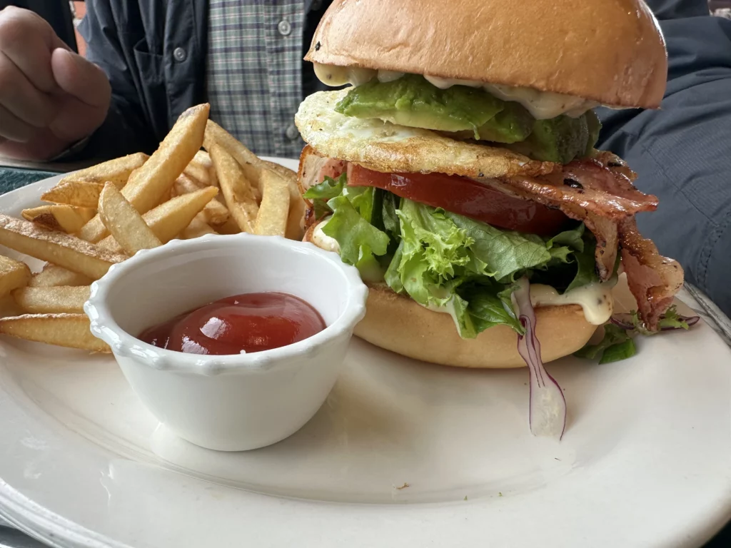 Burger & Chips at jeju brunch cafe Tangerine with brioche bun, avocado, fried egg, bacon, lettuce, tomato, and fries.