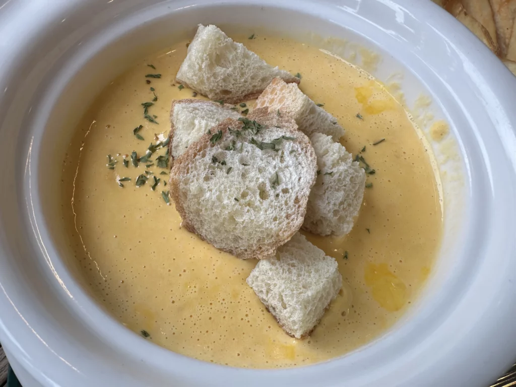 Signature Jeju carrot soup at jeju brunch cafe Tangerine served in a white bowl with croutons and parsley.