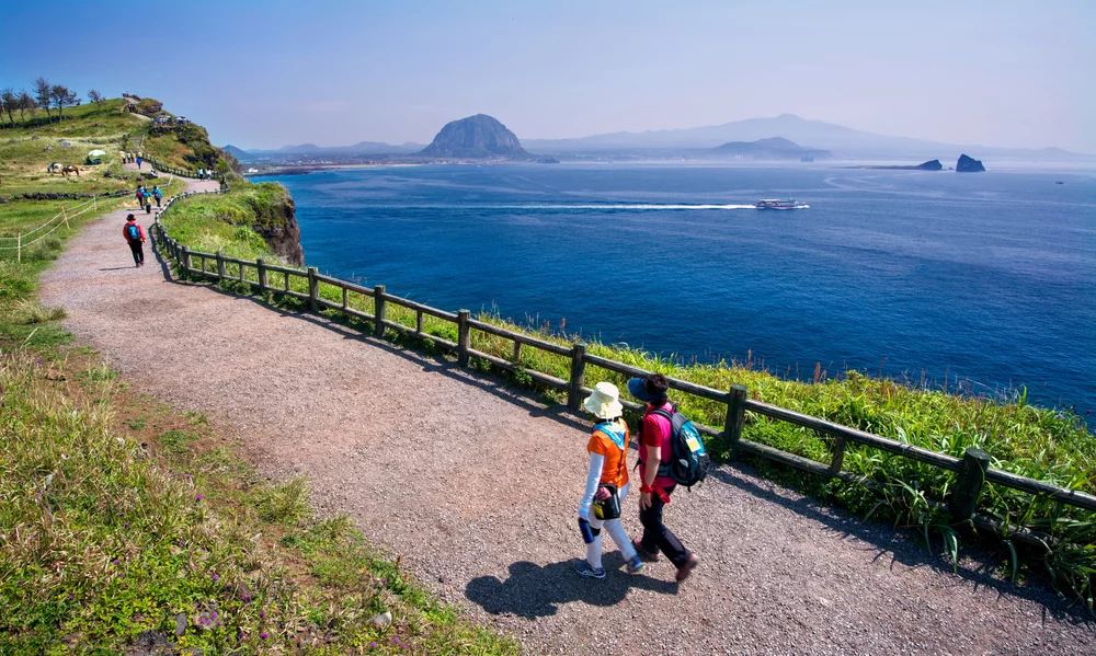 Hikers walking Jeju Olle Trail Course along the coast near the BTS favorite Jeju restaurant.