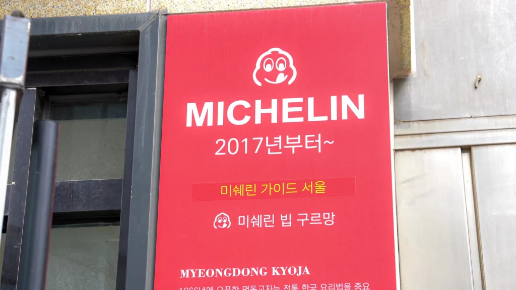 Michelin Bib Gourmand signboard outside Myeongdong Kyoja noting recognition by Michelin Guide Seoul since 2017.
