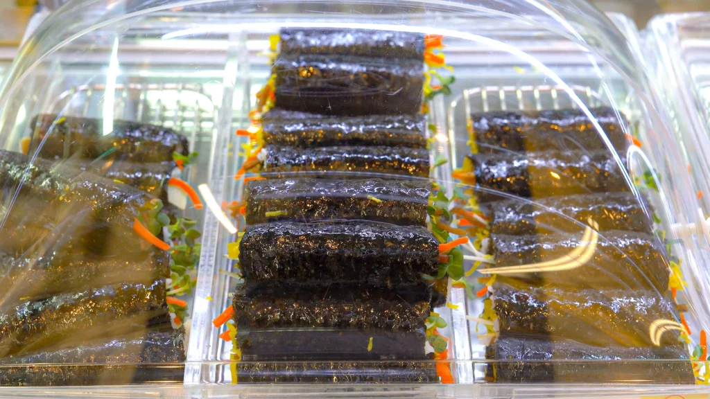 Freshly made chickgimbap mini gimbap rolls neatly arranged in a chilled bakery-style showcase ready for tourists to pick