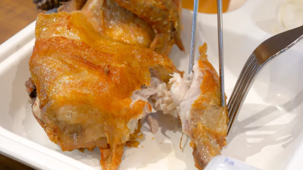 Close-up of crispy mahogany skin pulling away from juicy white meat on Yeongyang Center Myeongdong rotisserie tongdak.