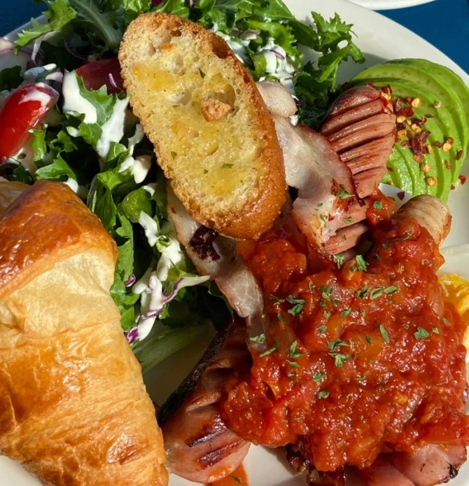 Tangerine Brunch plate at jeju brunch cafe Tangerine with sausage in tomato sauce, croissant, avocado, and fresh salad.